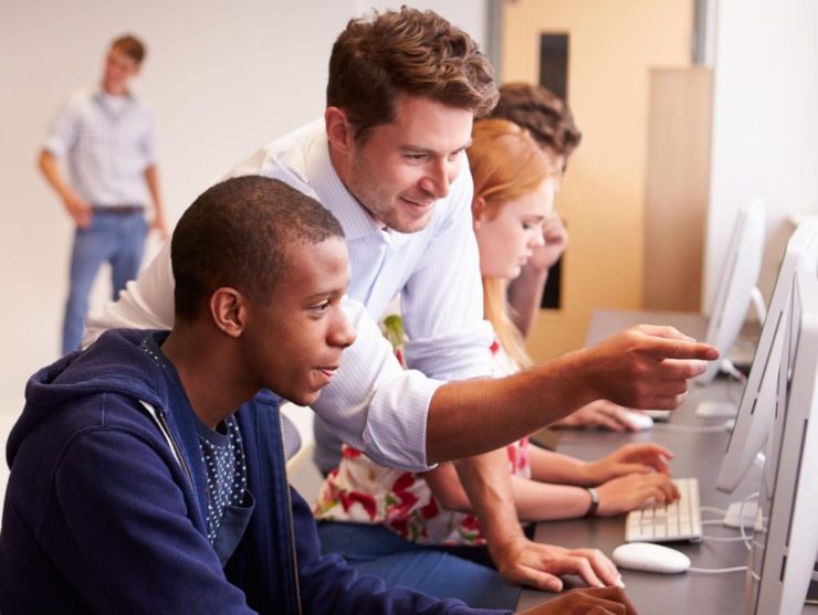 Teacher with students working at a computer together